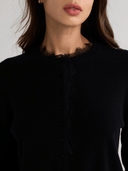 Close-up of black cashmere cardigan with delicate lace-trimmed crew neckline
